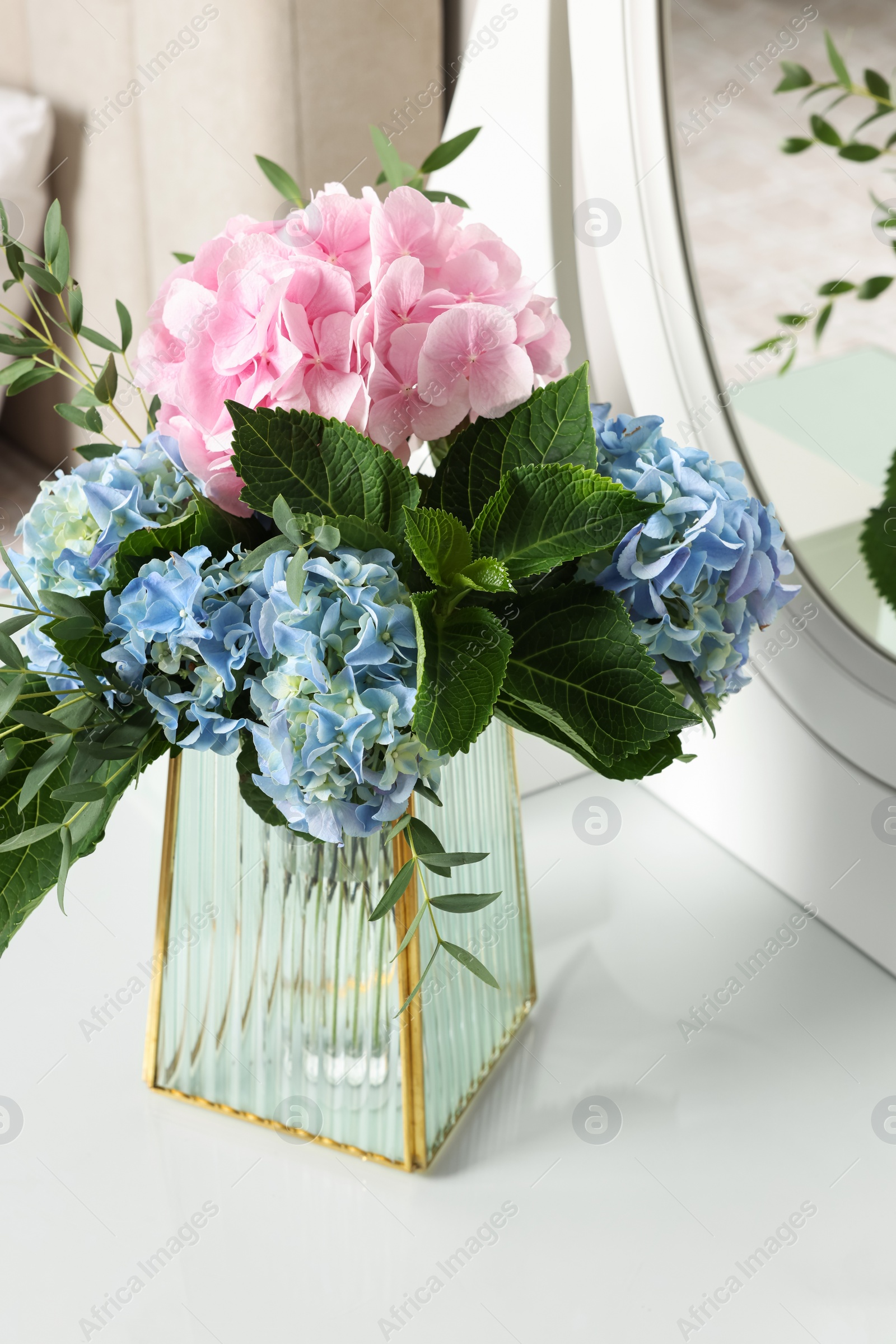 Photo of Beautiful hortensia flowers in vase on dressing table indoors