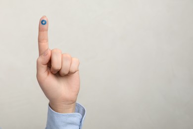 Photo of Woman showing blue circle drawn on finger against light grey background, closeup and space for text. World Diabetes Day