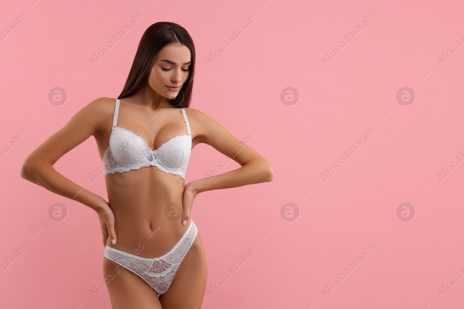 Photo of Young woman in elegant white underwear on pink background. Space for text