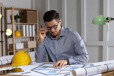 Architect working with construction drawings in office