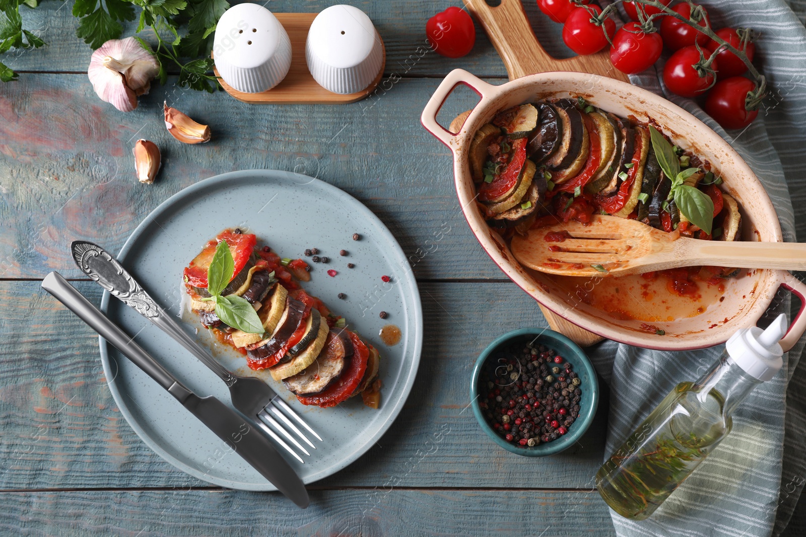 Photo of Delicious ratatouille served with basil on grey wooden table, flat lay