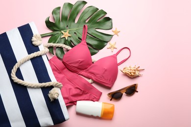 Photo of Stylish bag with beach accessories on pink background, flat lay