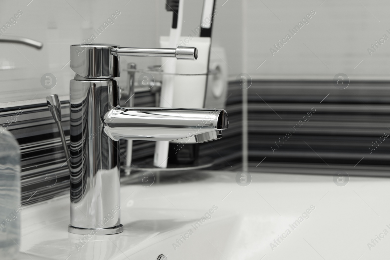 Photo of Clean white sink with shiny water tap in bathroom