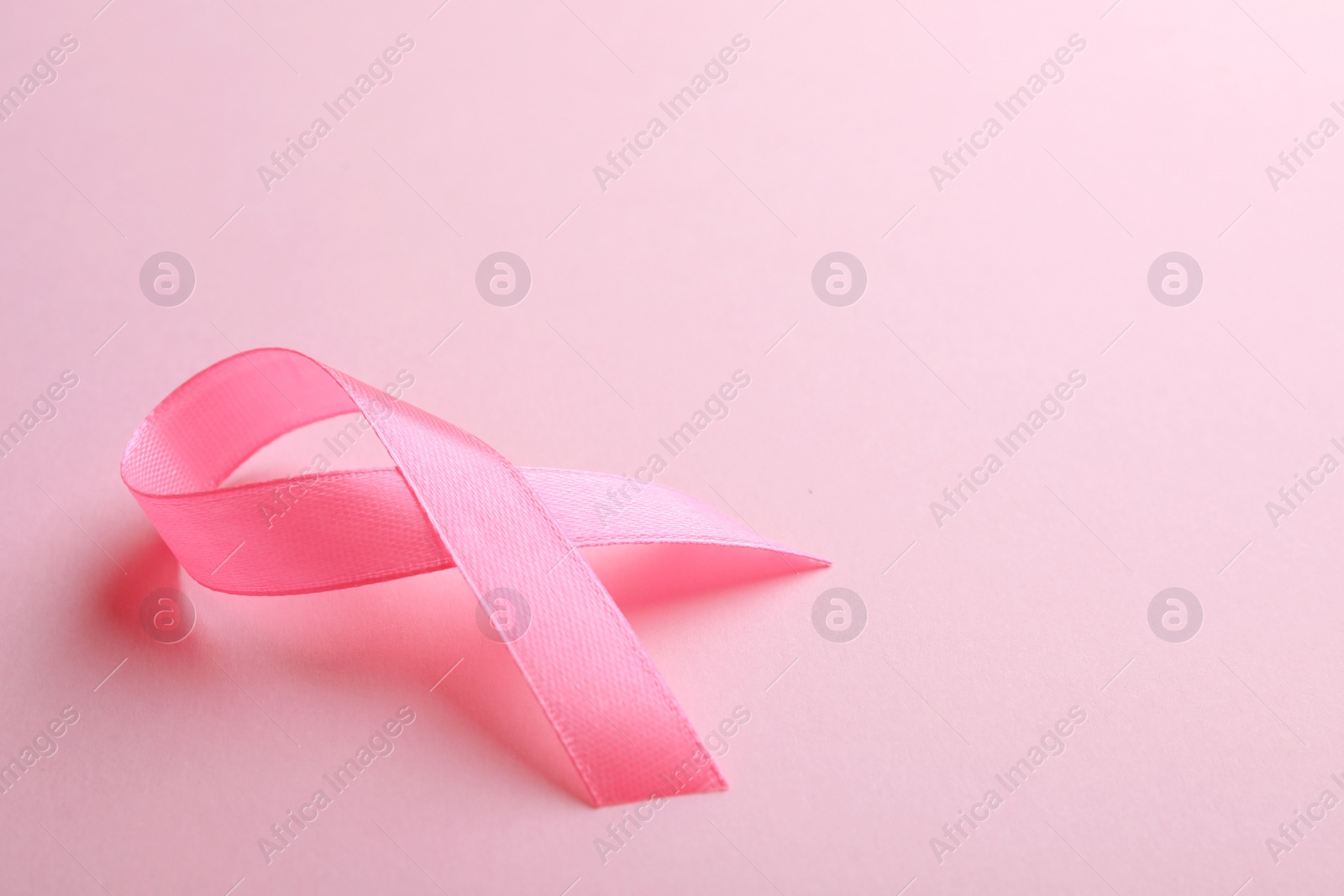 Photo of Pink ribbon on color background, space for text. Breast cancer awareness concept