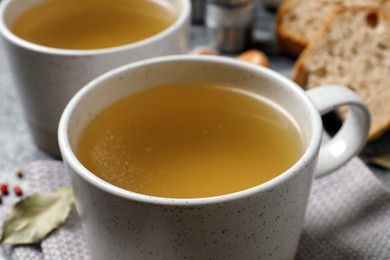 Hot delicious bouillon in cups on table, closeup