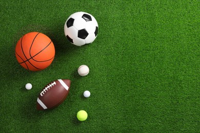 Photo of Many different sports balls on green grass, flat lay. Space for text