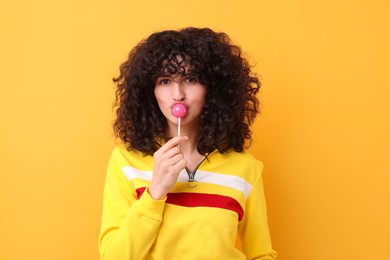 Beautiful woman with lollipop on yellow background