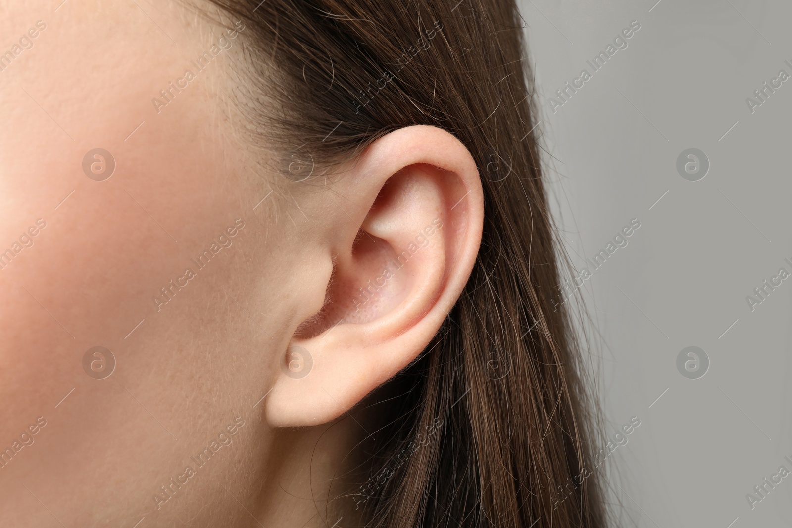 Photo of Woman touching her ear on light grey background, closeup