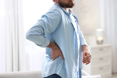 Photo of Man suffering from back pain at home, closeup. Bad posture problem