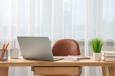 Photo of Home office. Stylish workplace with laptop and stationery on wooden desk indoors. Space for text