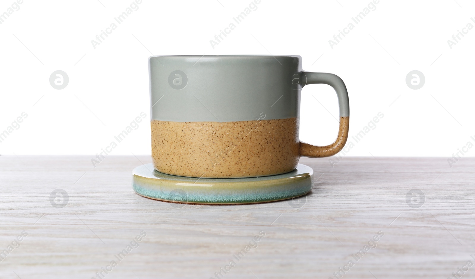 Photo of One ceramic mug with coaster on wooden table against white background