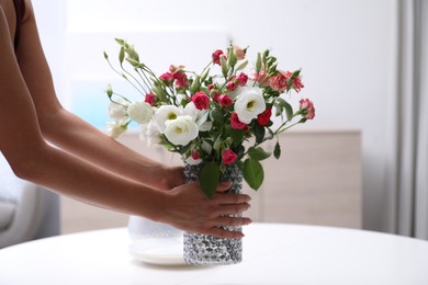 Photo of Woman and vase with beautiful flowers on white table in room, closeup