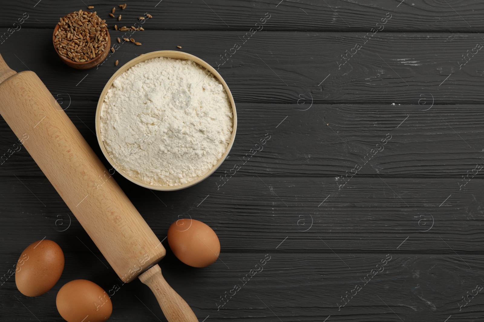 Photo of Flat lay composition with wheat flour and eggs on black wooden table. Space for text