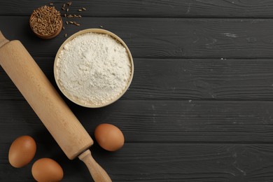 Photo of Flat lay composition with wheat flour and eggs on black wooden table. Space for text