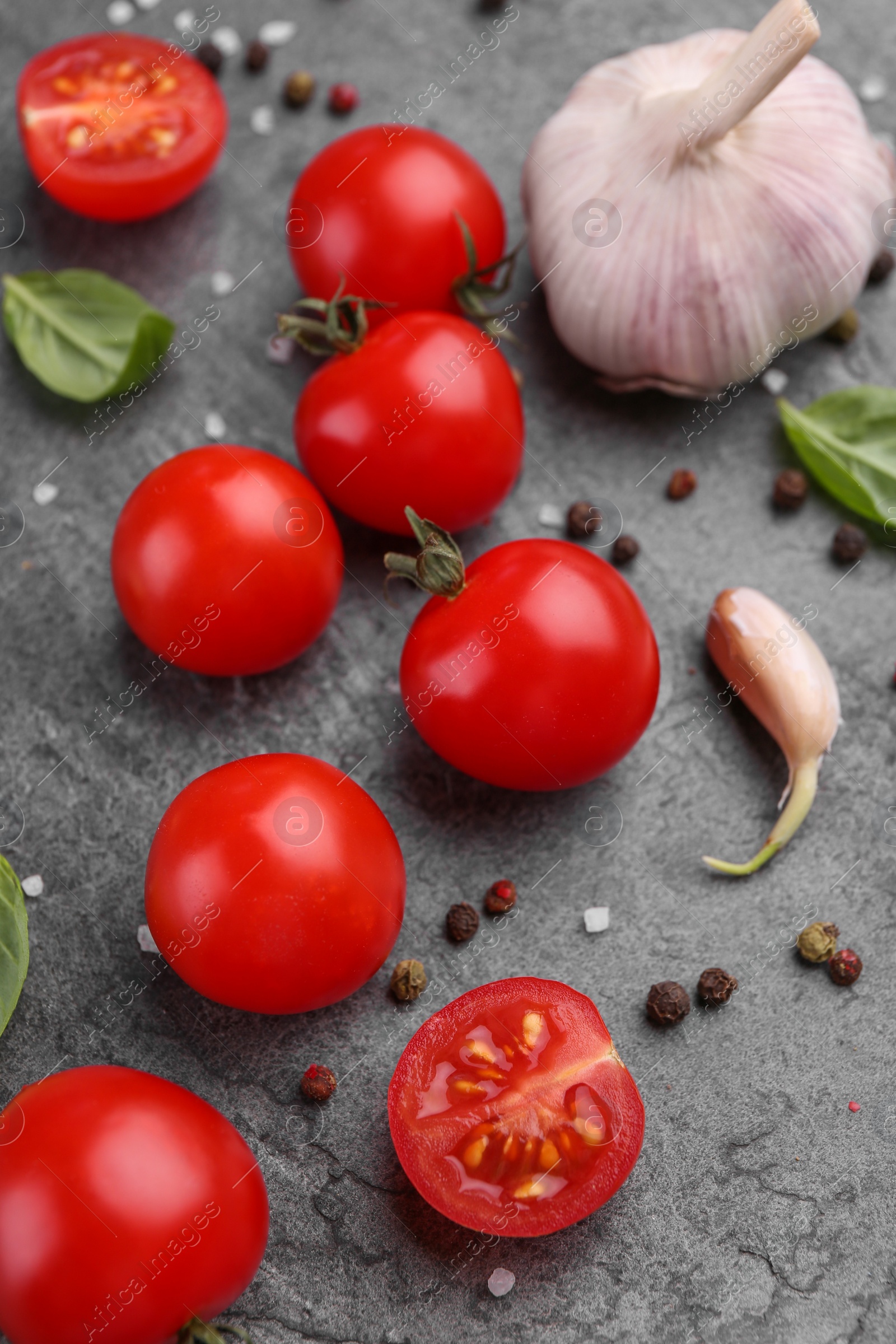 Photo of Ripe tomatoes, garlic and spices on gray textured table, above view