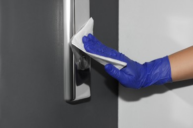 Photo of Woman wiping elevator call panel with paper napkin, closeup