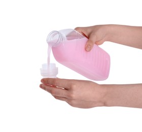 Photo of Woman pouring fabric softener from bottle into cap on white background, closeup