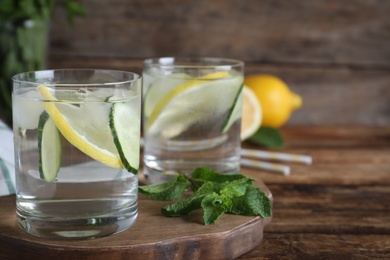 Photo of Refreshing water with cucumber, lemon and mint on wooden table, closeup. Space for text