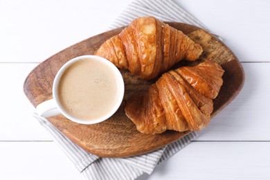 Tasty breakfast. Cup of coffee and croissants on white wooden table, top view