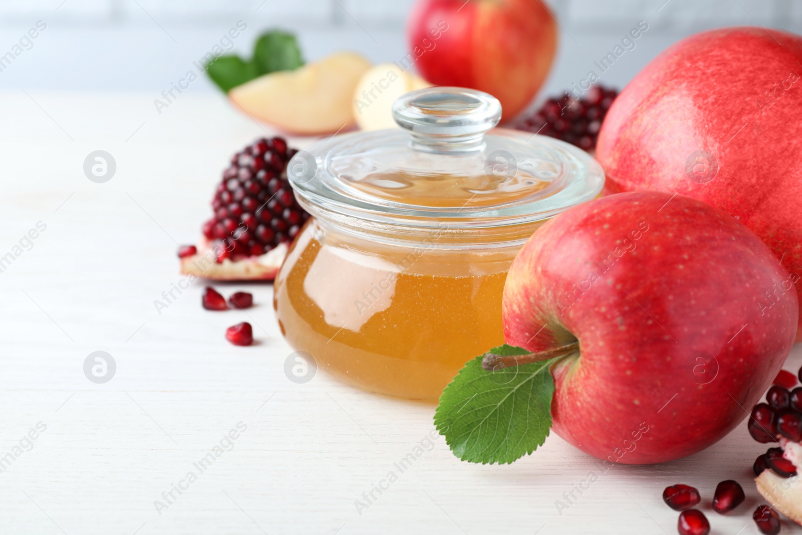 Photo of Honey, pomegranate and apples on white wooden table, closeup. Rosh Hashana holiday