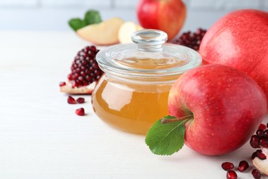 Photo of Honey, pomegranate and apples on white wooden table, closeup. Rosh Hashana holiday