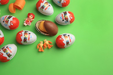 Sveti Vlas, Bulgaria - June 26, 2023: Kinder Surprise Eggs, plastic containers and toys on light green background, flat lay. Space for text