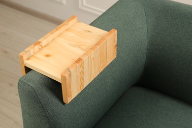 Photo of Wooden armrest table on sofa in room. Interior element