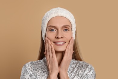 Woman massaging her face on beige background