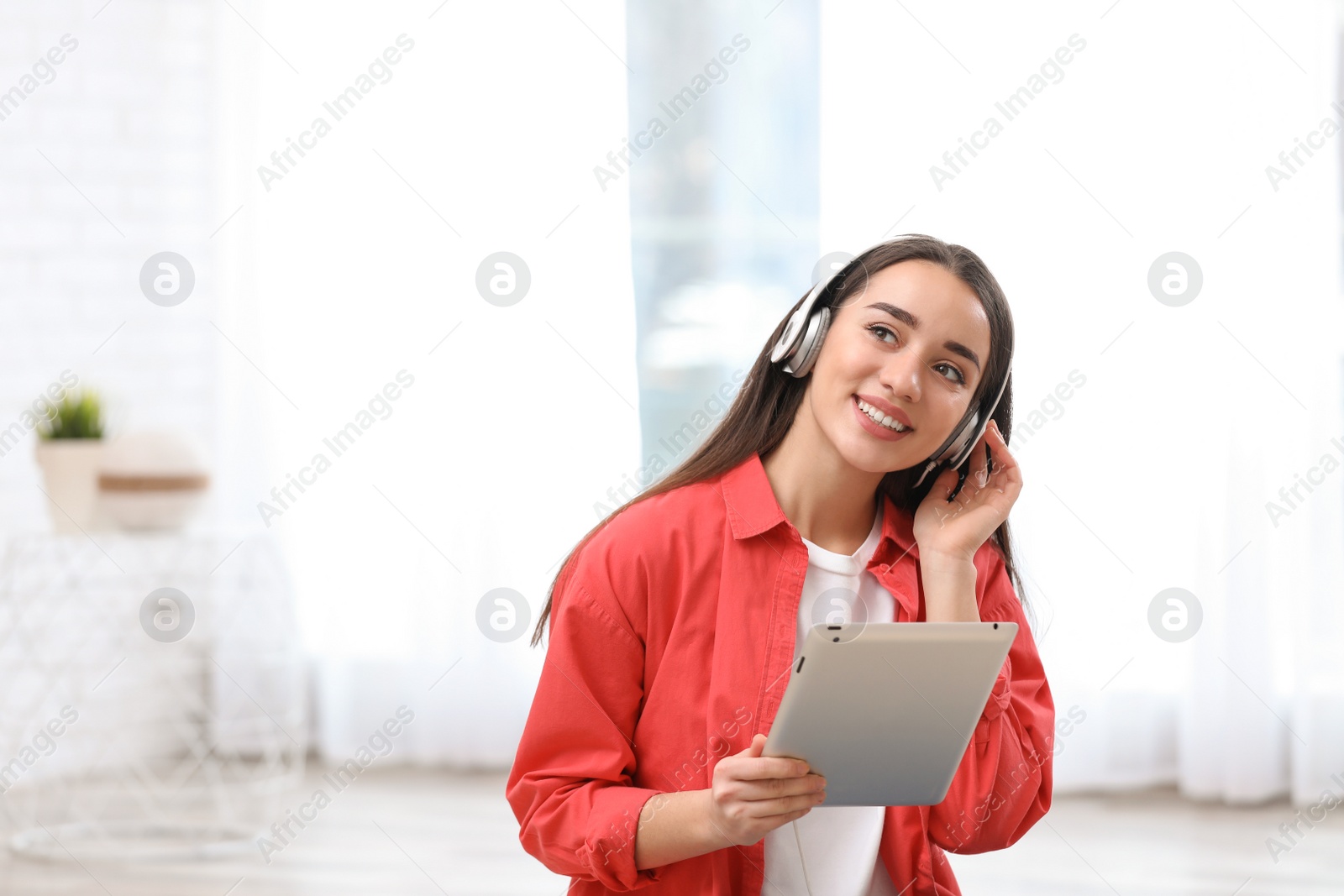 Photo of Young woman with headphones enjoying music in living room