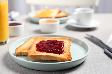 Photo of Fresh toasts with jam for breakfast on light grey table