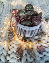 Photo of Beautiful Christmas tree baubles and fairy lights on white knitted fabric