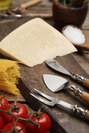 Photo of Cheese knives and fork on wooden board, closeup. Cooking utensils