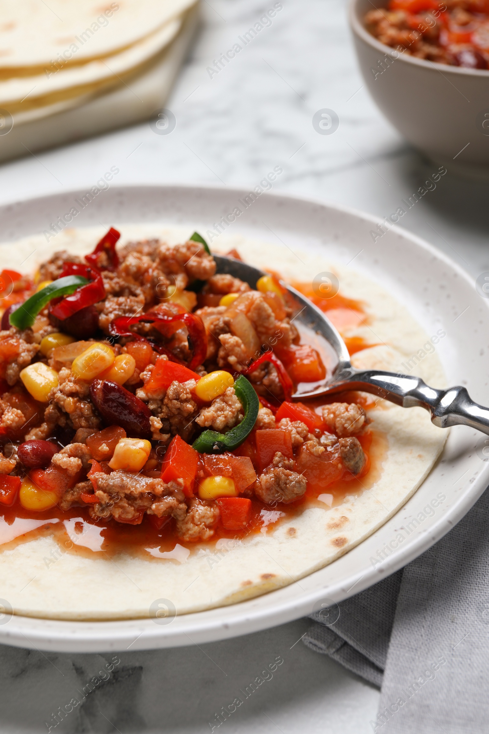 Photo of Tasty chili con carne with tortilla on white table