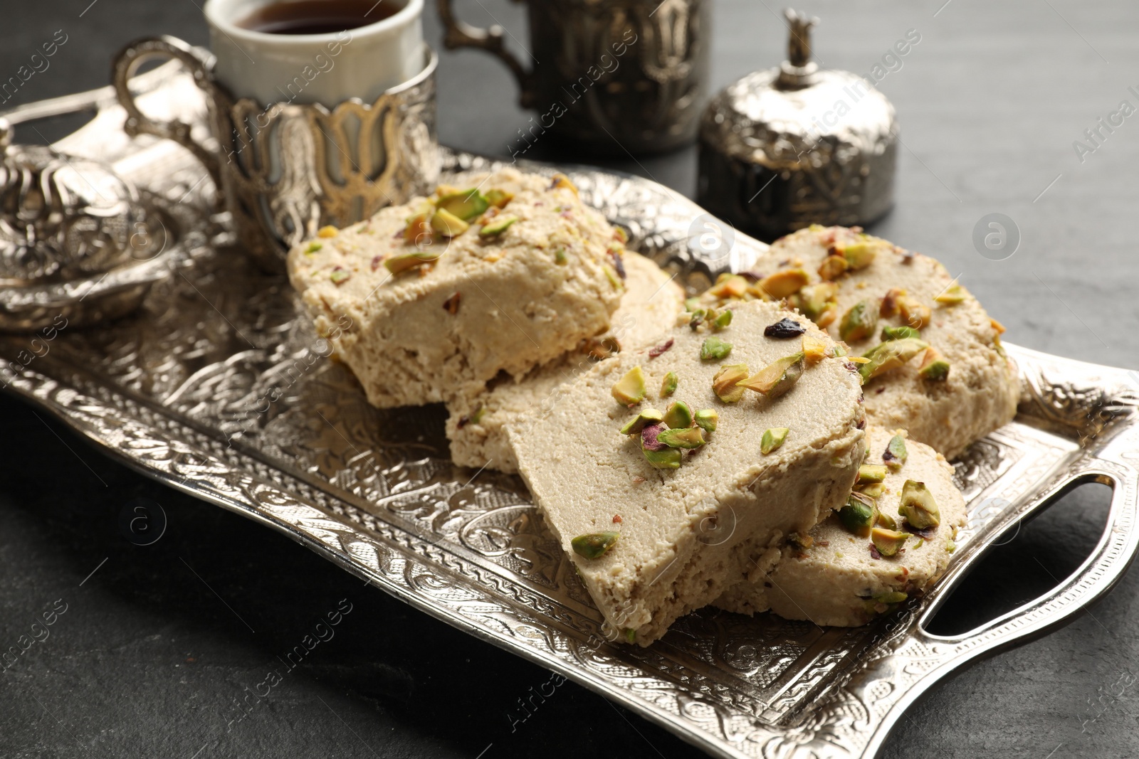 Photo of Tasty pistachio halva served on grey table, closeup