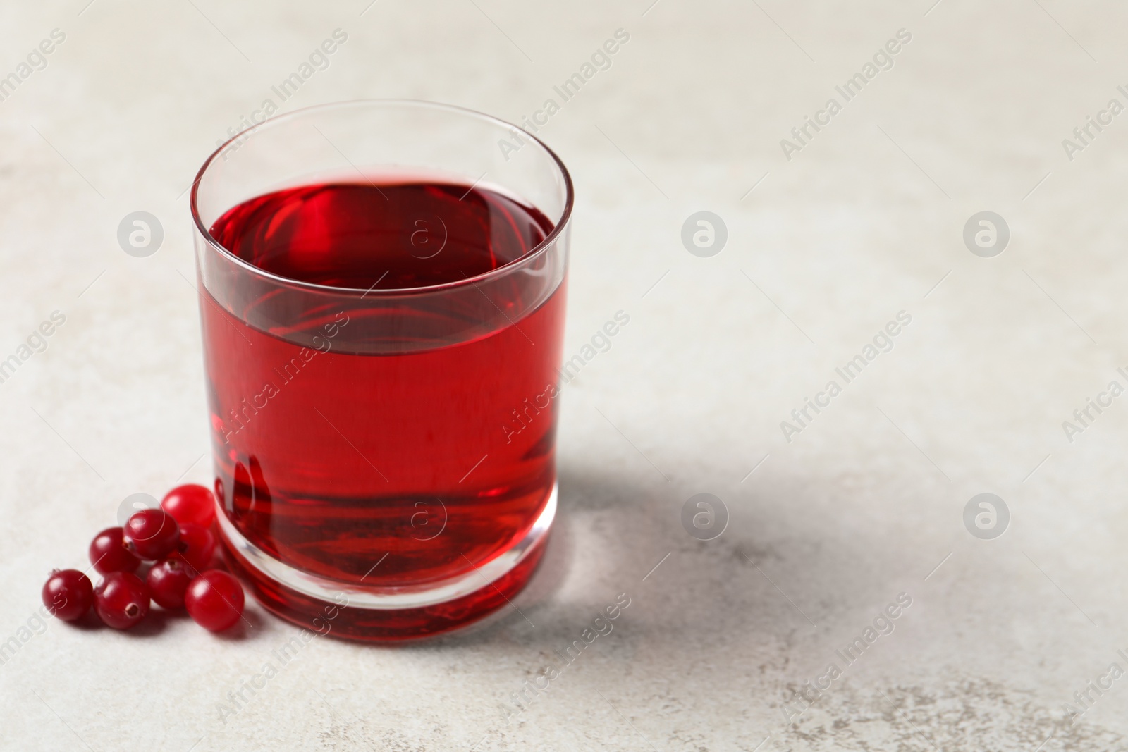 Photo of Tasty refreshing cranberry juice and fresh berries on light table. Space for text