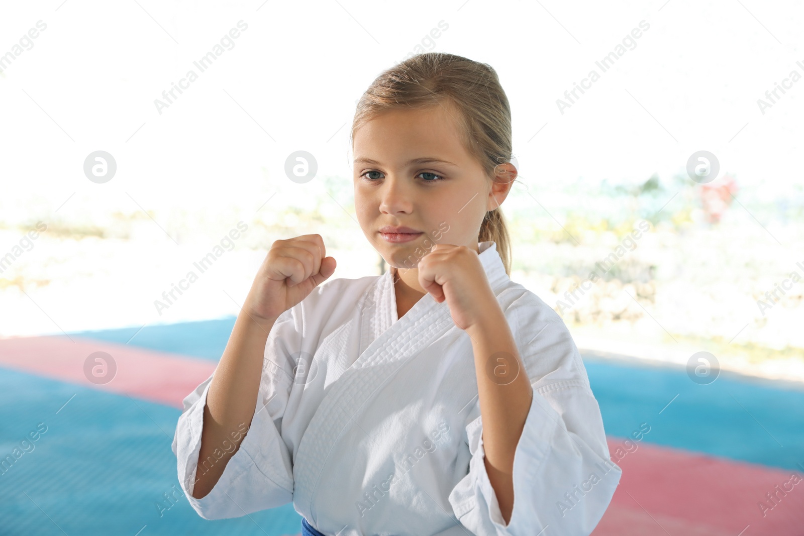 Photo of Girl in kimono practicing karate on tatami outdoors