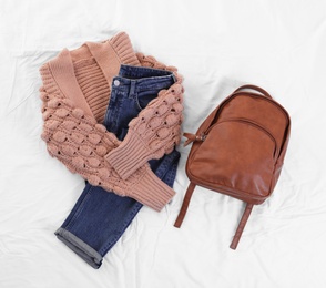 Photo of Flat lay composition with jeans, cardigan and backpack on white fabric