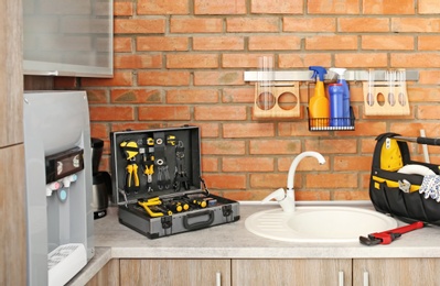 Photo of Set of plumber's tools near sink on kitchen counter