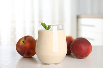 Photo of Tasty milk shake and fresh peaches on white table
