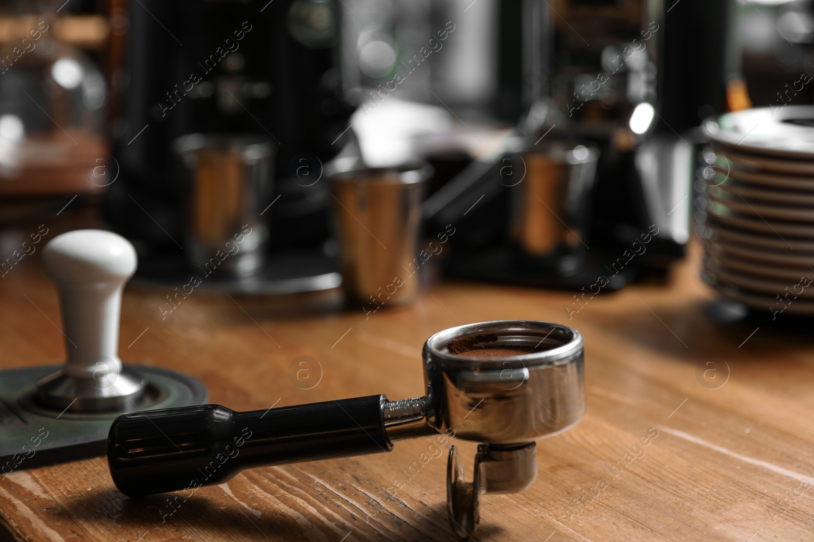 Photo of Portafilter with milled coffee on wooden bar counter. Space for text