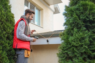 Photo of Young man decorating roof with Christmas lights