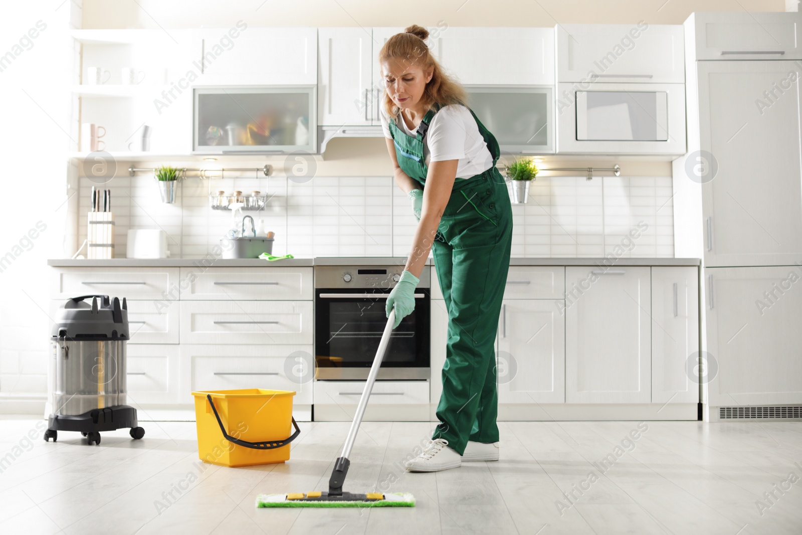 Photo of Professional janitor cleaning floor with mop in kitchen