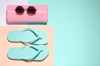 Towel, flip flops and sunglasses on color background, flat lay with space for text. Beach objects