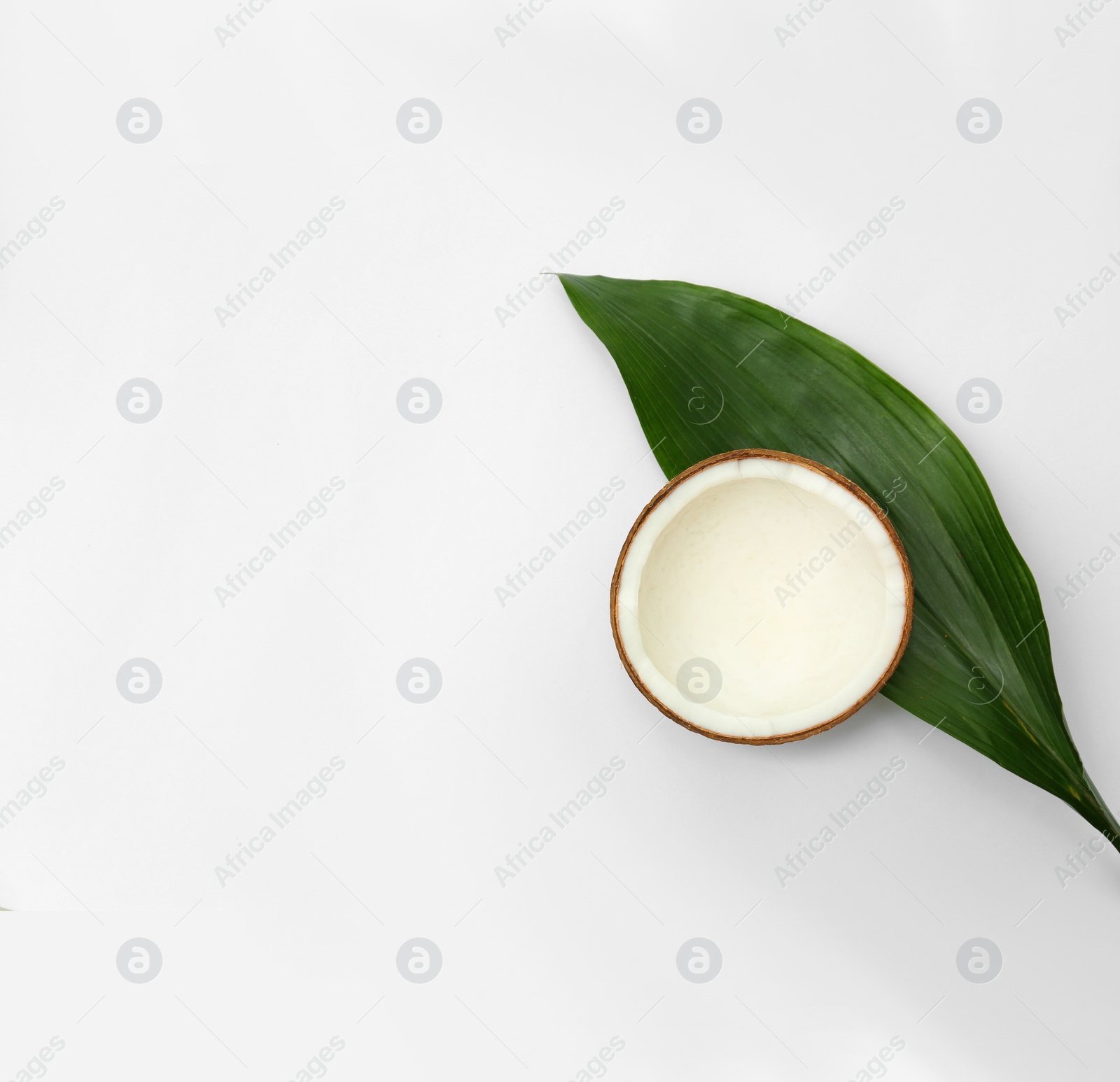 Photo of Half of fresh coconut and palm leaf on white background, top view