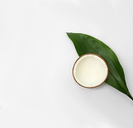 Photo of Half of fresh coconut and palm leaf on white background, top view