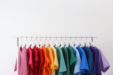 Rack with bright clothes on white background. Rainbow colors