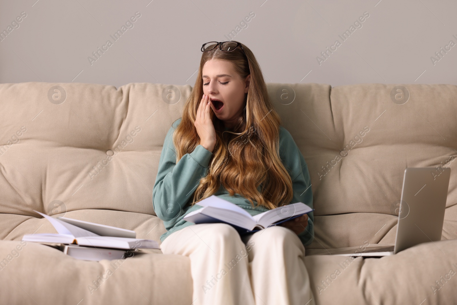 Photo of Young tired woman studying on couch indoors