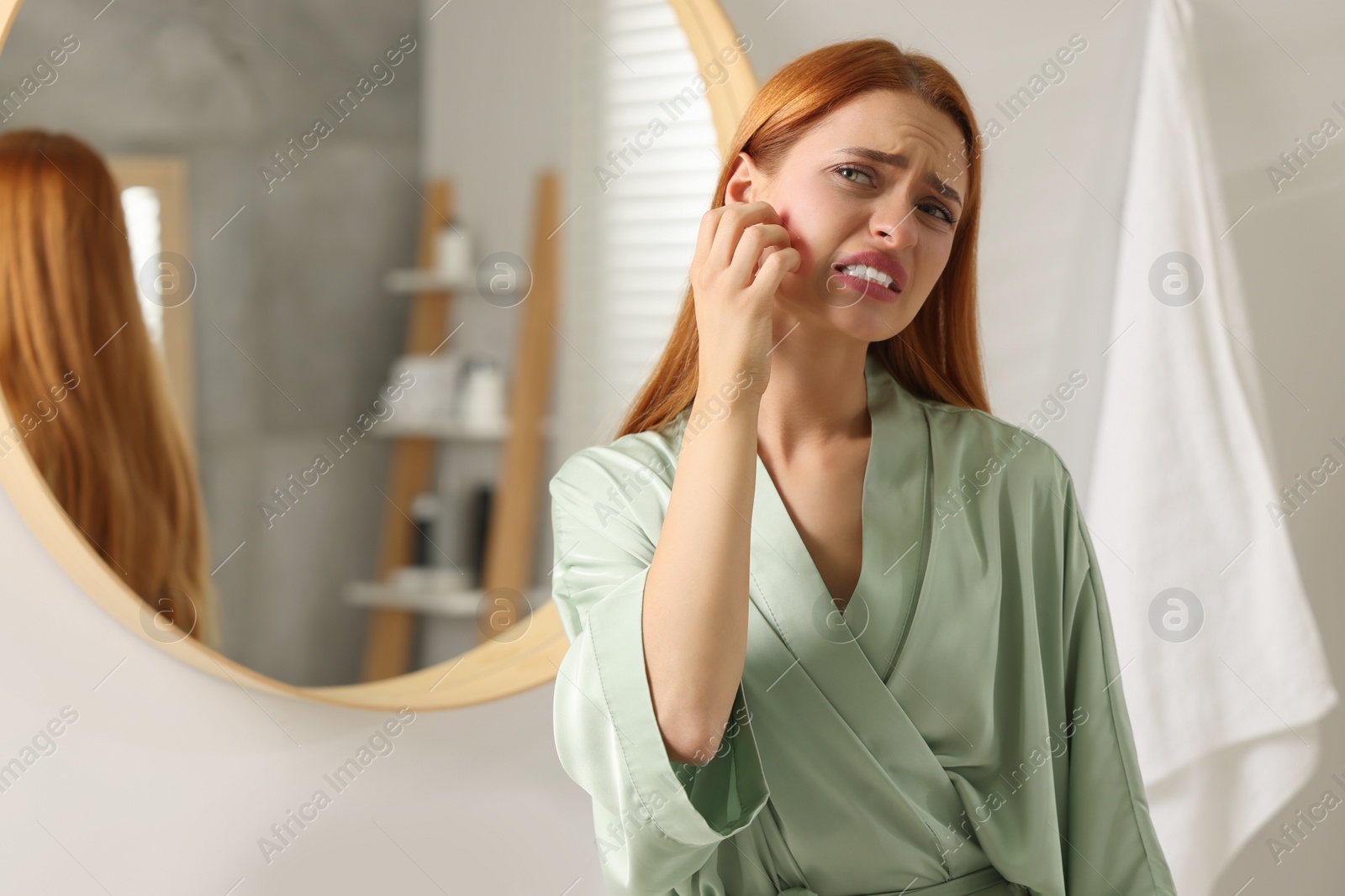 Photo of Suffering from allergy. Young woman scratching her face in bathroom, space for text