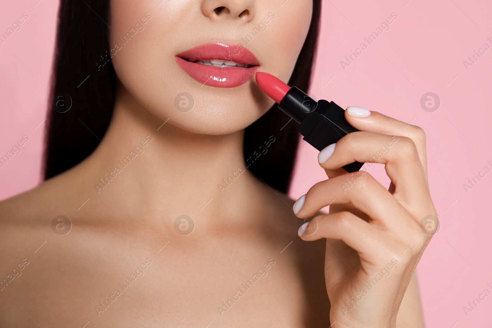 Image of Young woman with beautiful makeup holding glossy lipstick on pink background, closeup