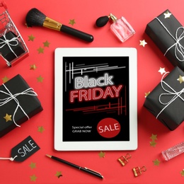Photo of Flat lay composition with tablet, gifts and accessories on red background. Black Friday sale